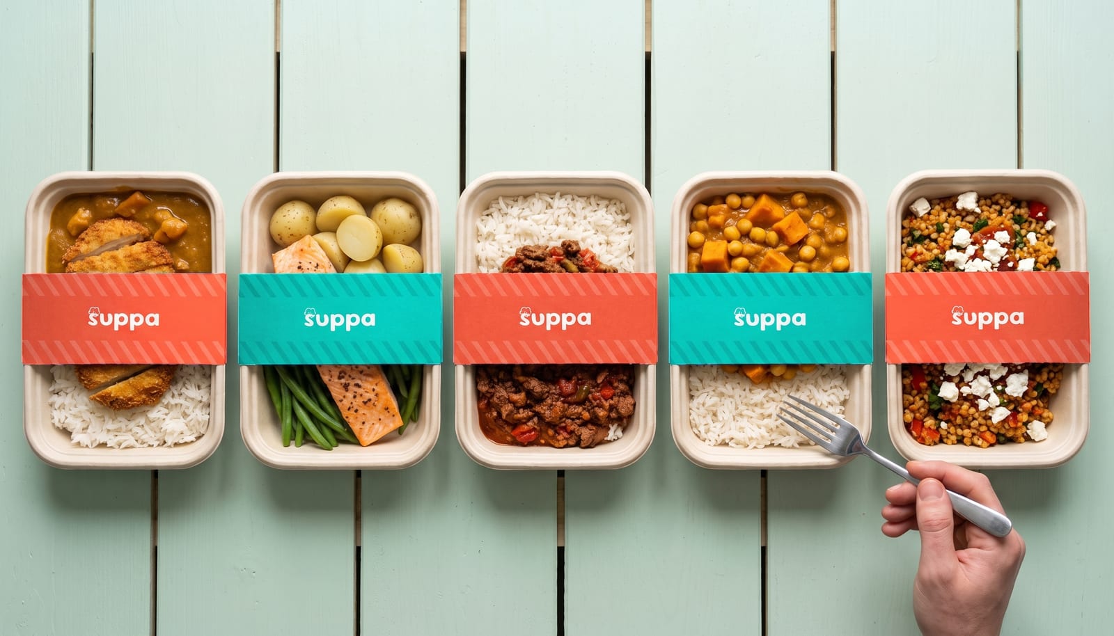 Five open Suppa meal trays on a mint table, with their teal sleeves and lids beside them